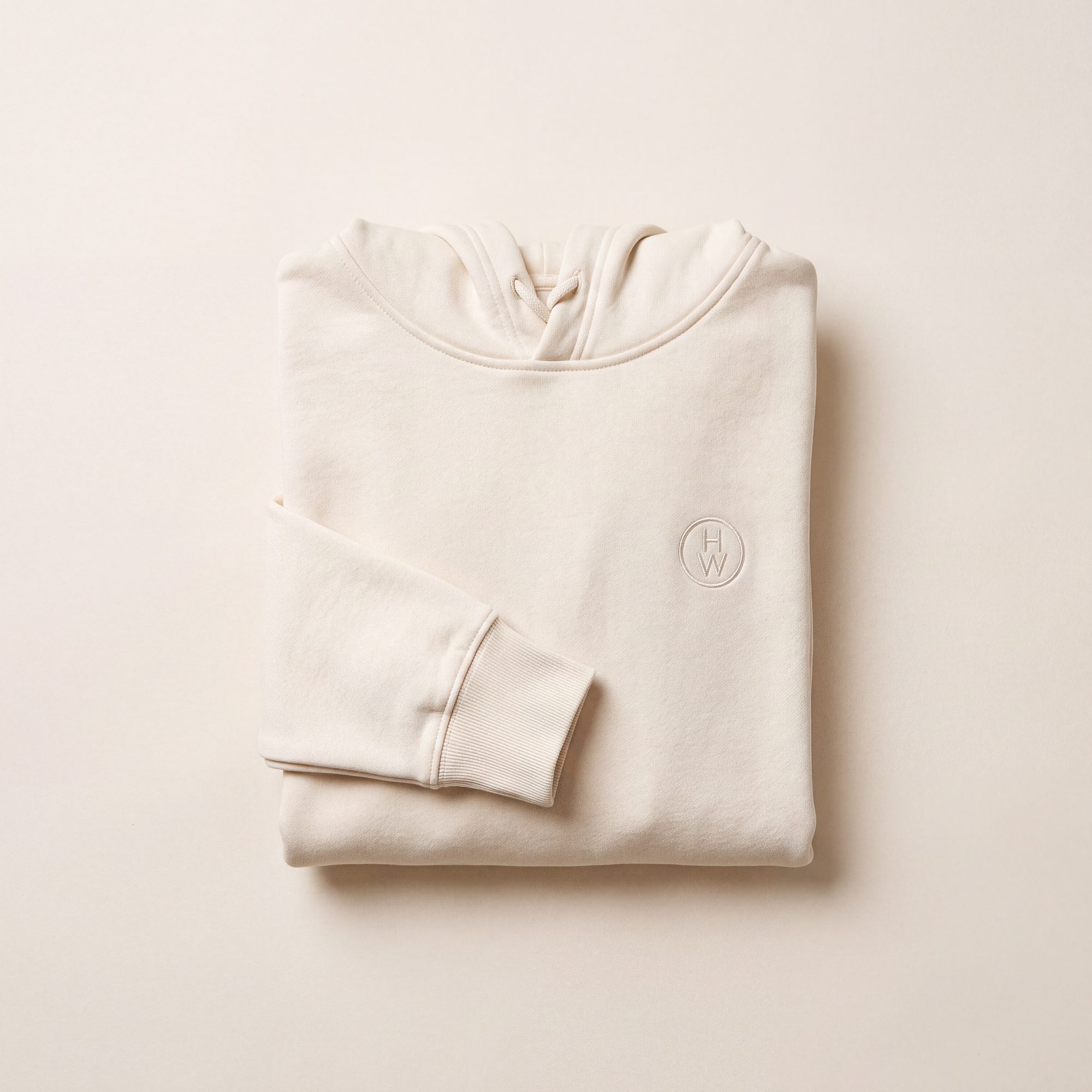 Cream hoodie with tonal embroidered emblem, folded flat