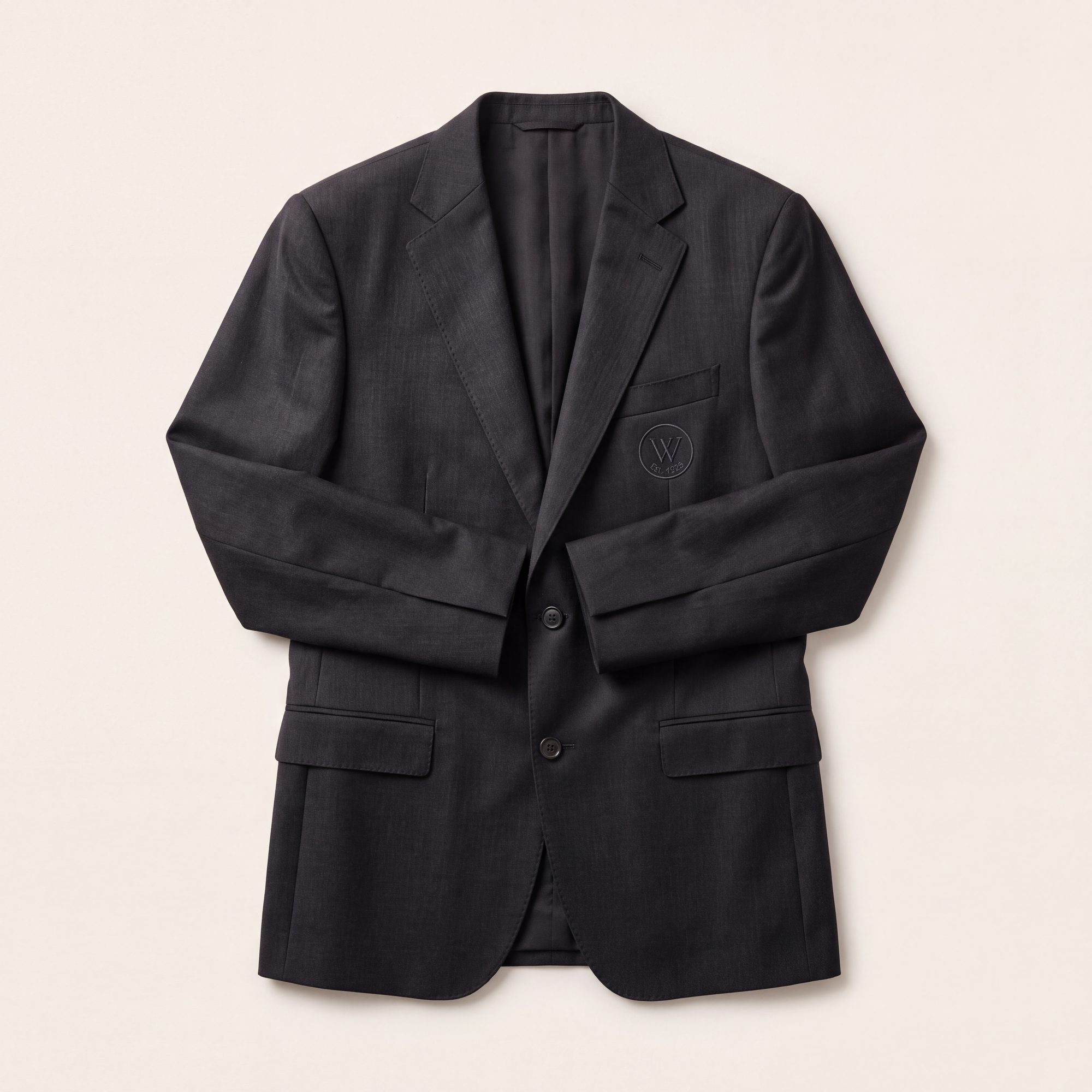 Charcoal tailored jacket with tonal embroidered emblem, laid flat